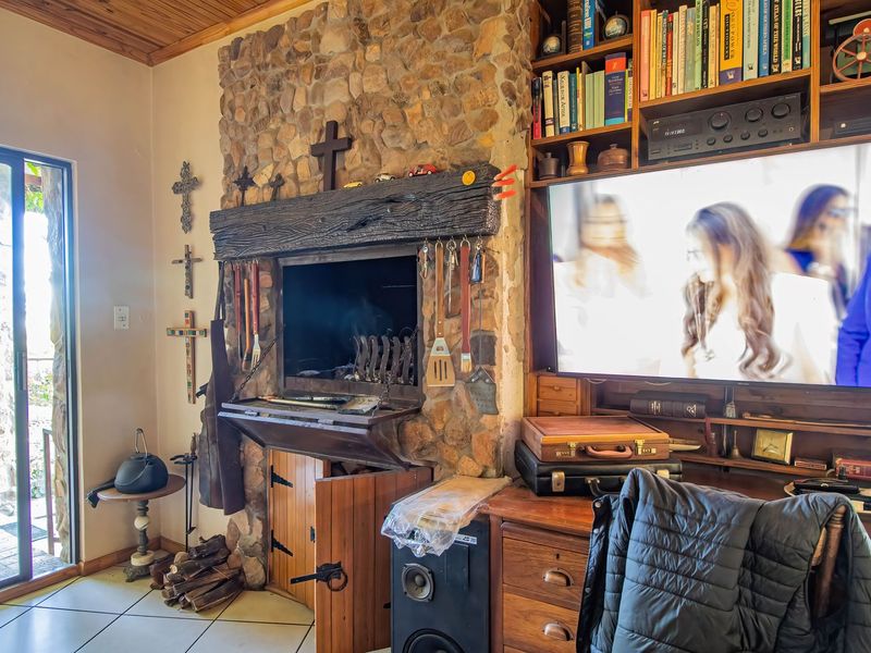 Cozy living area featuring a prominent stone fireplace with a timber mantel, built-in shelving, and direct access to an outdoor patio through sliding glass doors.