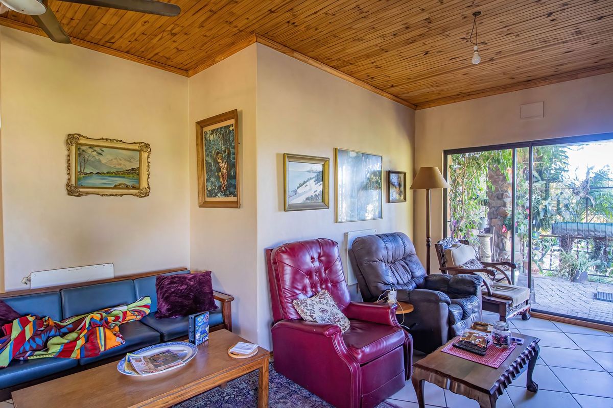 A living room featuring a timber-clad ceiling, tiled flooring, and large sliding glass doors providing access to an outdoor patio area.