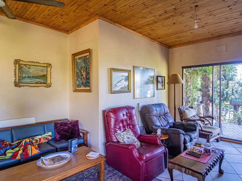 A living room featuring a timber-clad ceiling, tiled flooring, and large sliding glass doors providing access to an outdoor patio area.