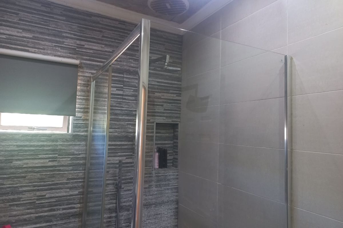 Modern bathroom featuring a walk-in glass shower enclosure, tiled walls with textured stone-look accents, and a built-in shower niche.