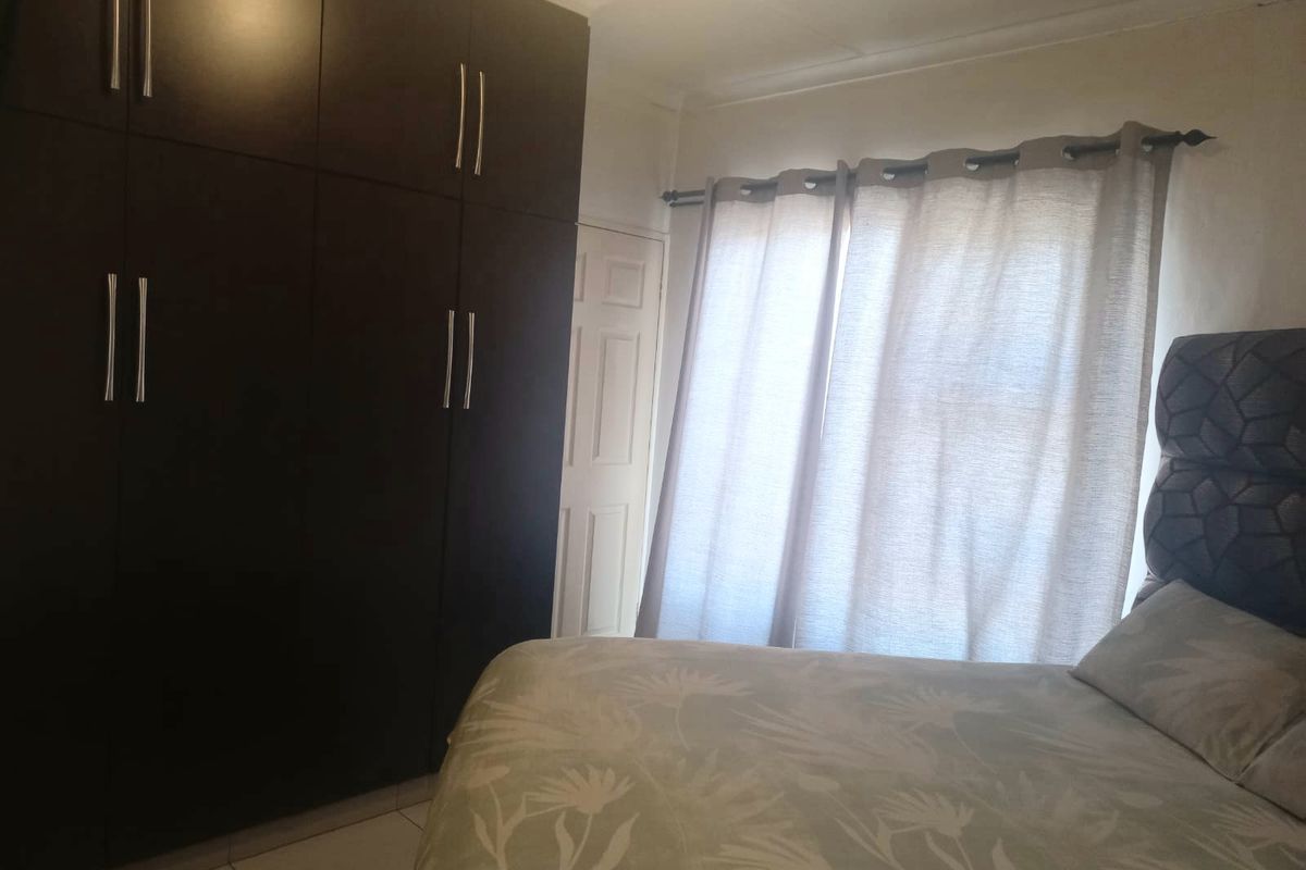 A bedroom featuring dark built-in cupboards and tiled flooring, providing functional storage space.