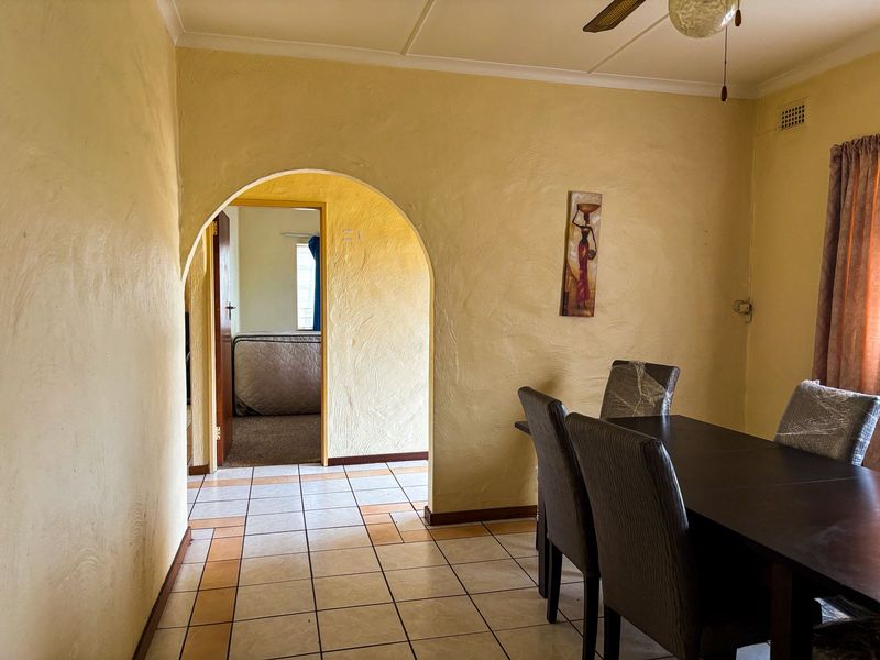 Dining area featuring a distinctive arched doorway, tiled flooring, and a ceiling fan, leading into an adjacent bedroom space.