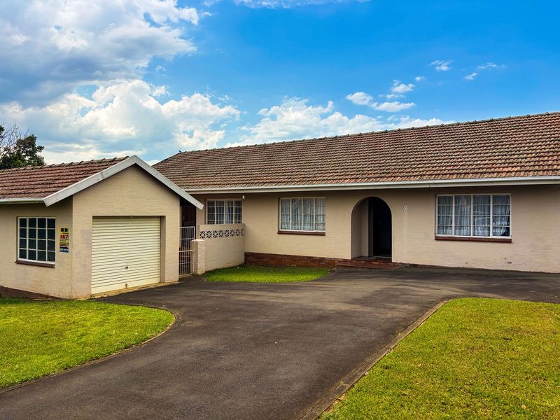 Front elevation of a single-story house featuring a tiled roof, attached garage, and a paved driveway with landscaped lawn.
