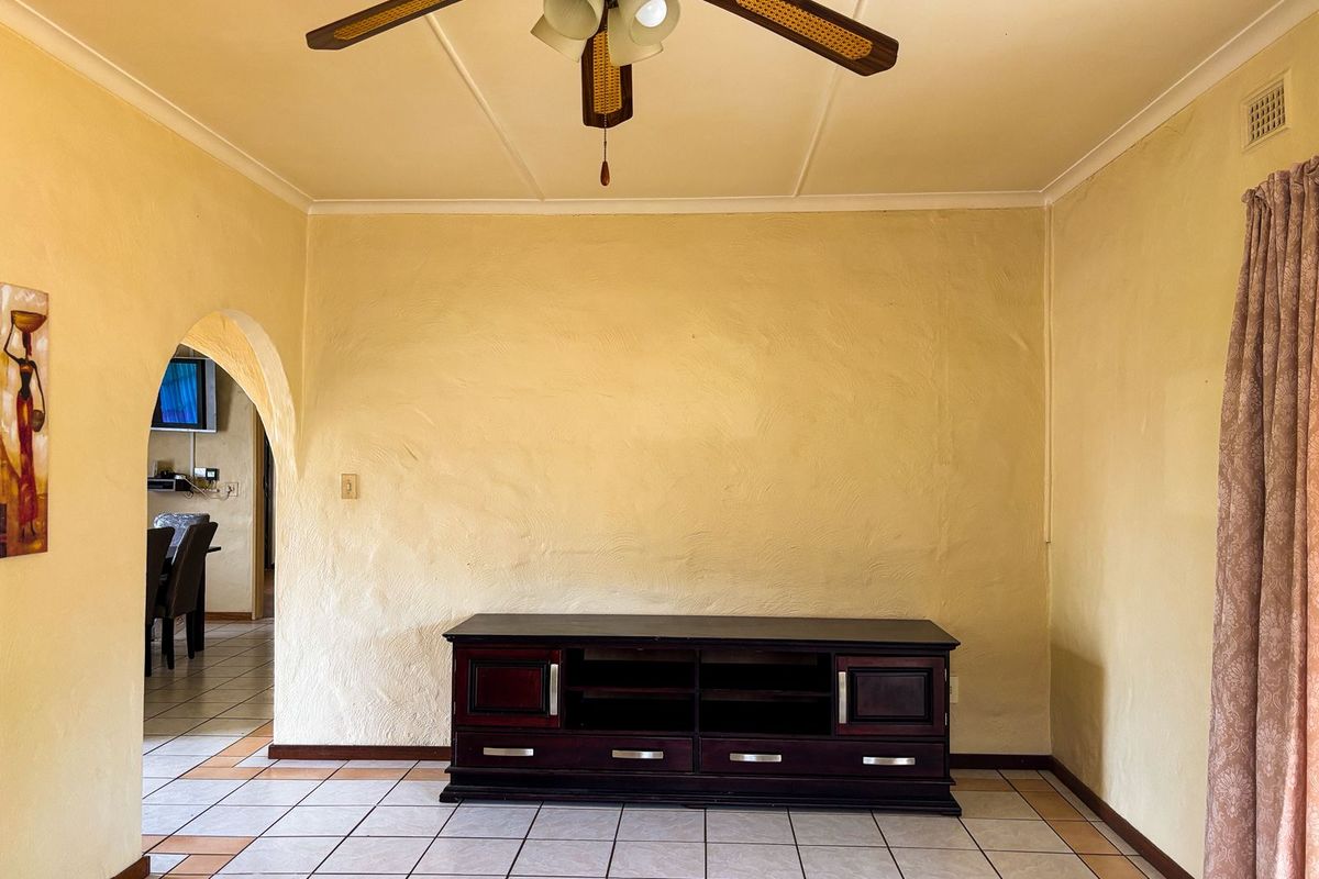 A living room featuring ceramic floor tiles, a ceiling fan, and an arched doorway leading to an adjacent space.