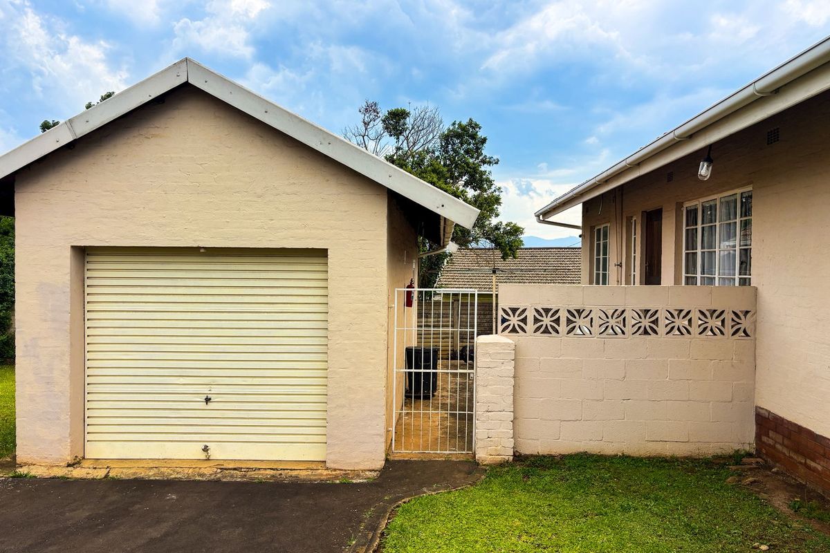 Rear exterior view featuring a single garage with a roller door, a security gate, and a decorative breeze block wall.