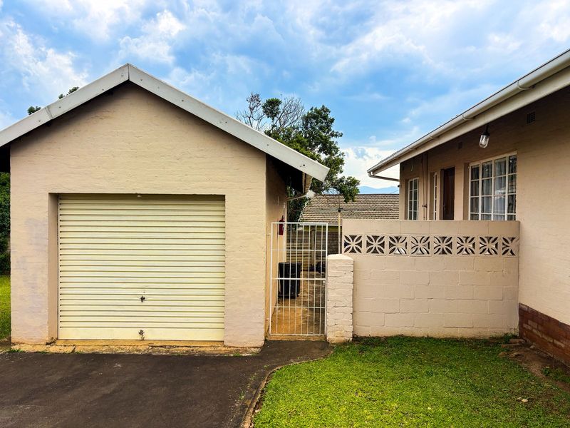Rear exterior view featuring a single garage with a roller door, a security gate, and a decorative breeze block wall.