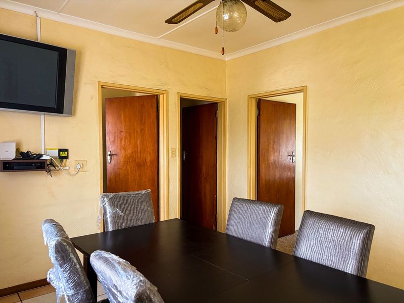 Dining area featuring a ceiling fan and access to three separate rooms through traditional wooden doors.