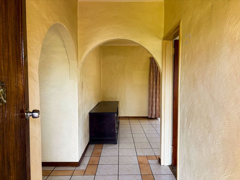 A hallway featuring distinctive arched doorways, textured walls, and tiled flooring, providing a transitional space between rooms.