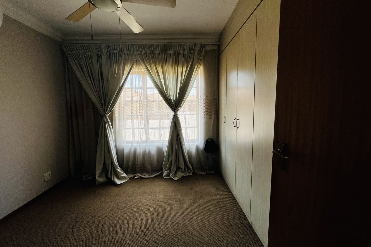 A bedroom featuring built-in cupboards, a ceiling fan, and carpeted flooring, offering a functional and private living space.