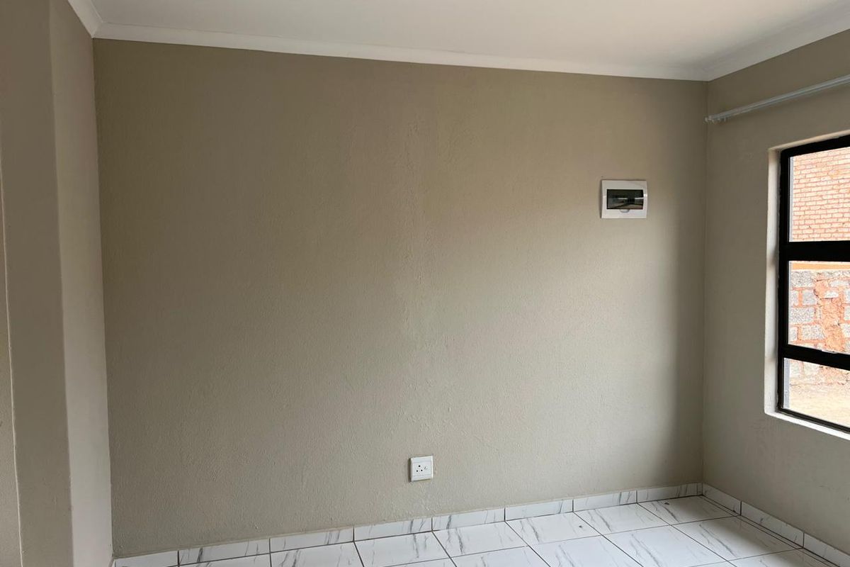 A clean, empty room featuring neutral painted walls, modern marble-look floor tiles, and a built-in electrical distribution board.