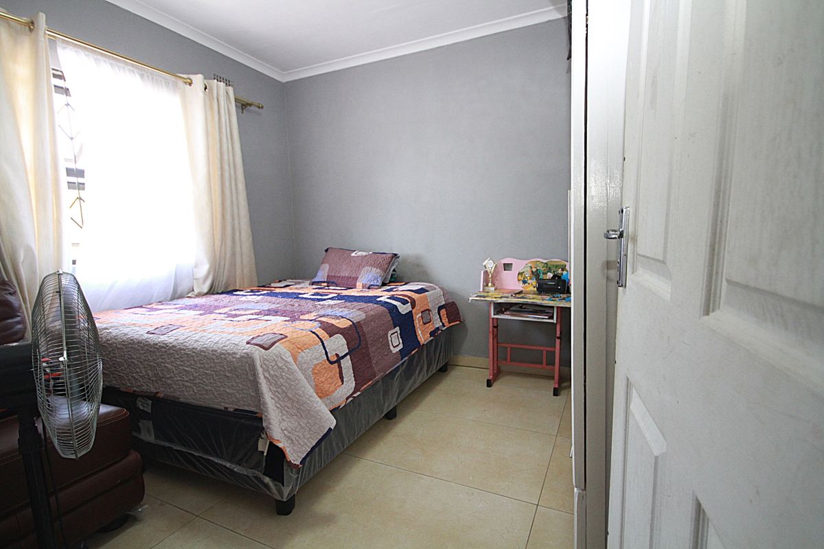 A functional bedroom featuring tiled flooring, neutral wall tones, and a window providing natural light.