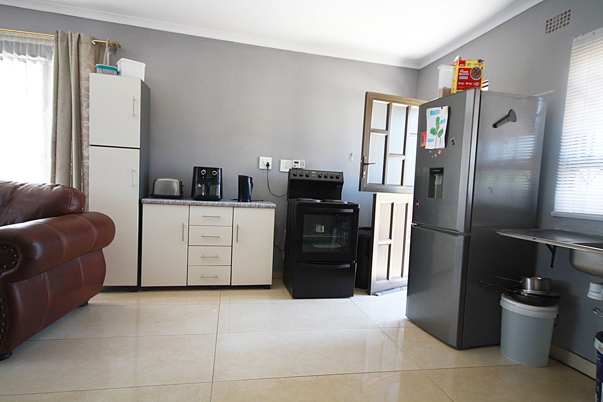A functional kitchen area featuring built-in cabinetry, a freestanding stove, and tiled flooring, providing a practical space for daily meal preparation.