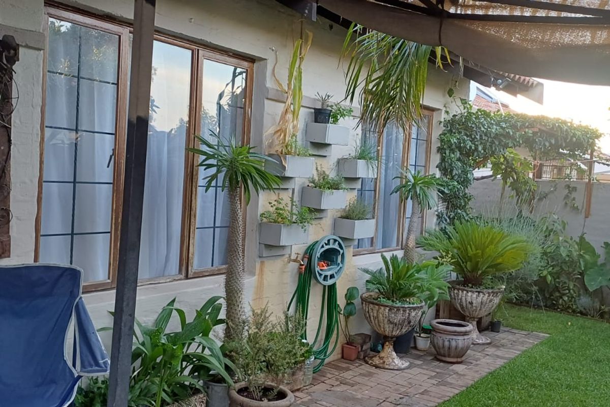 A rear garden area featuring brick paving, timber-framed windows, and wall-mounted planters, providing a cozy outdoor space for relaxation.