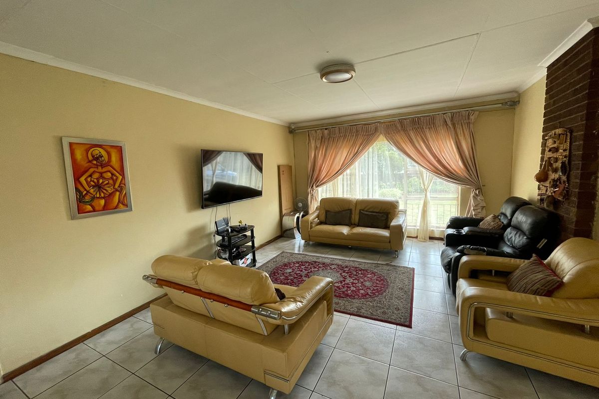 Spacious living room featuring tiled flooring and a classic brick fireplace, offering a comfortable and functional layout for relaxation.