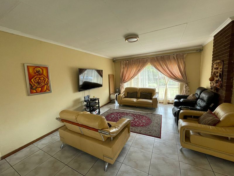 Spacious living room featuring tiled flooring and a classic brick fireplace, offering a comfortable and functional layout for relaxation.