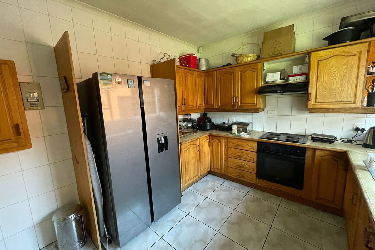 A functional kitchen featuring wooden cabinetry, tiled splashbacks, and built-in cooking appliances, offering a classic layout with potential for modern updates.
