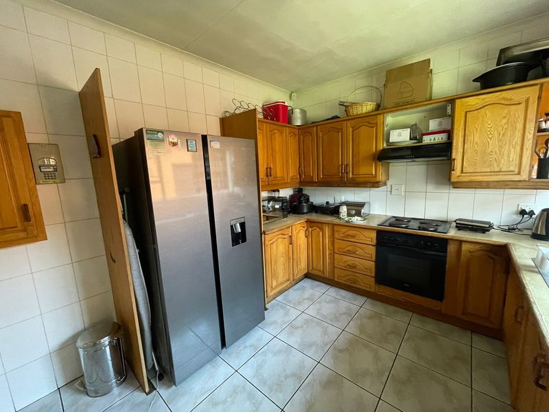 A functional kitchen featuring wooden cabinetry, tiled splashbacks, and built-in cooking appliances, offering a classic layout with potential for modern updates.
