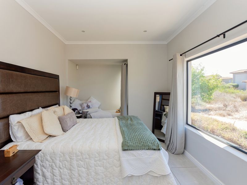 A well-maintained bedroom featuring tiled flooring, recessed lighting, and a large window providing natural light and exterior views.