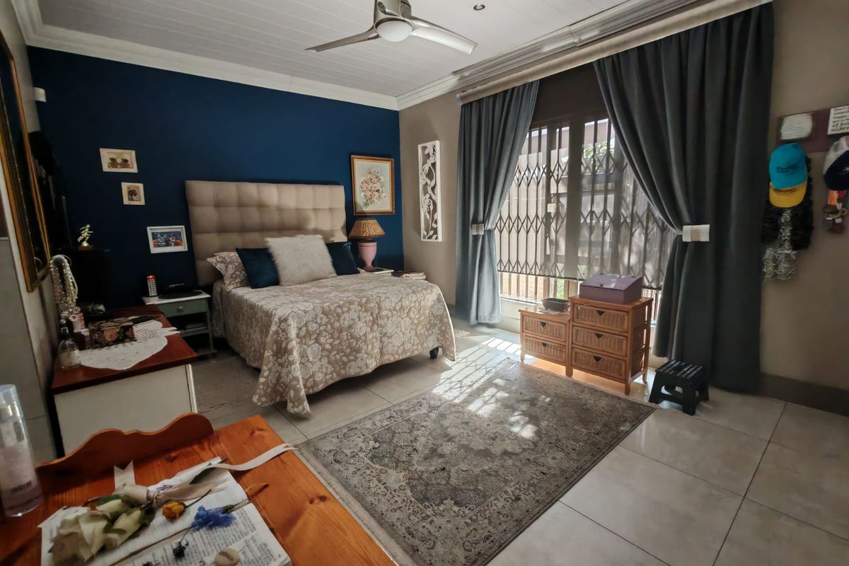 A well-maintained bedroom featuring tiled flooring, a ceiling fan, and a secure window with a fitted security gate.