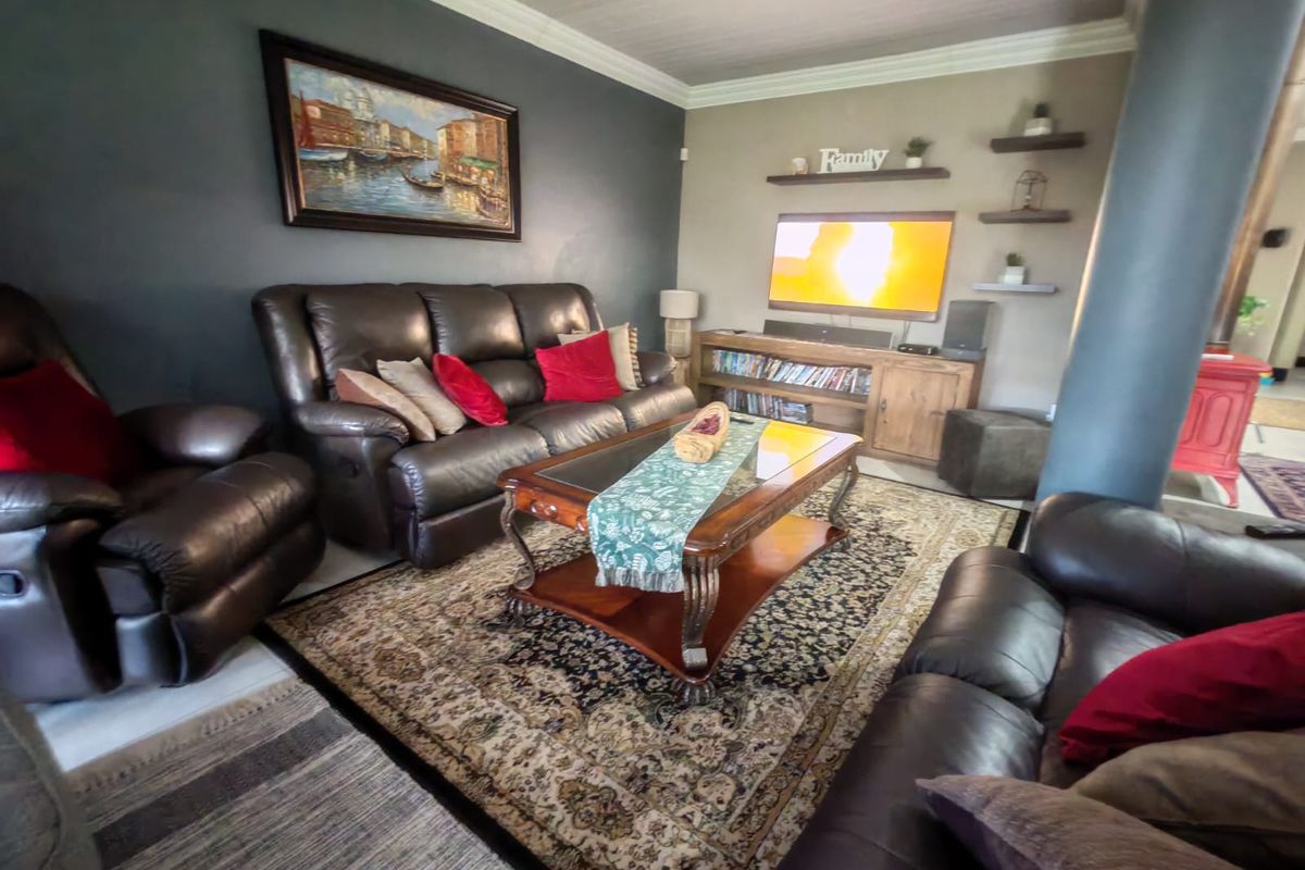 A comfortable living room featuring dark accent walls, crown molding, recessed lighting, and a prominent structural column.