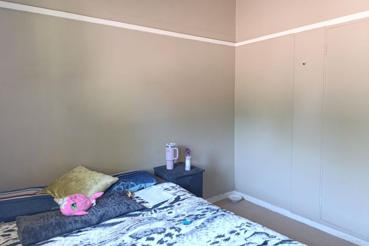 A bedroom featuring a built-in cupboard and traditional picture rail detailing, requiring some cosmetic attention to the wall finishes.