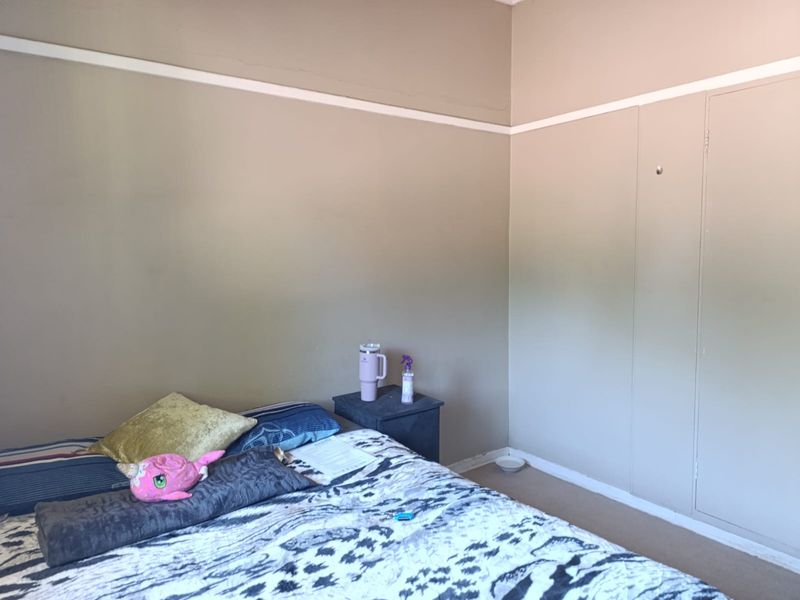 A bedroom featuring a built-in cupboard and traditional picture rail detailing, requiring some cosmetic attention to the wall finishes.