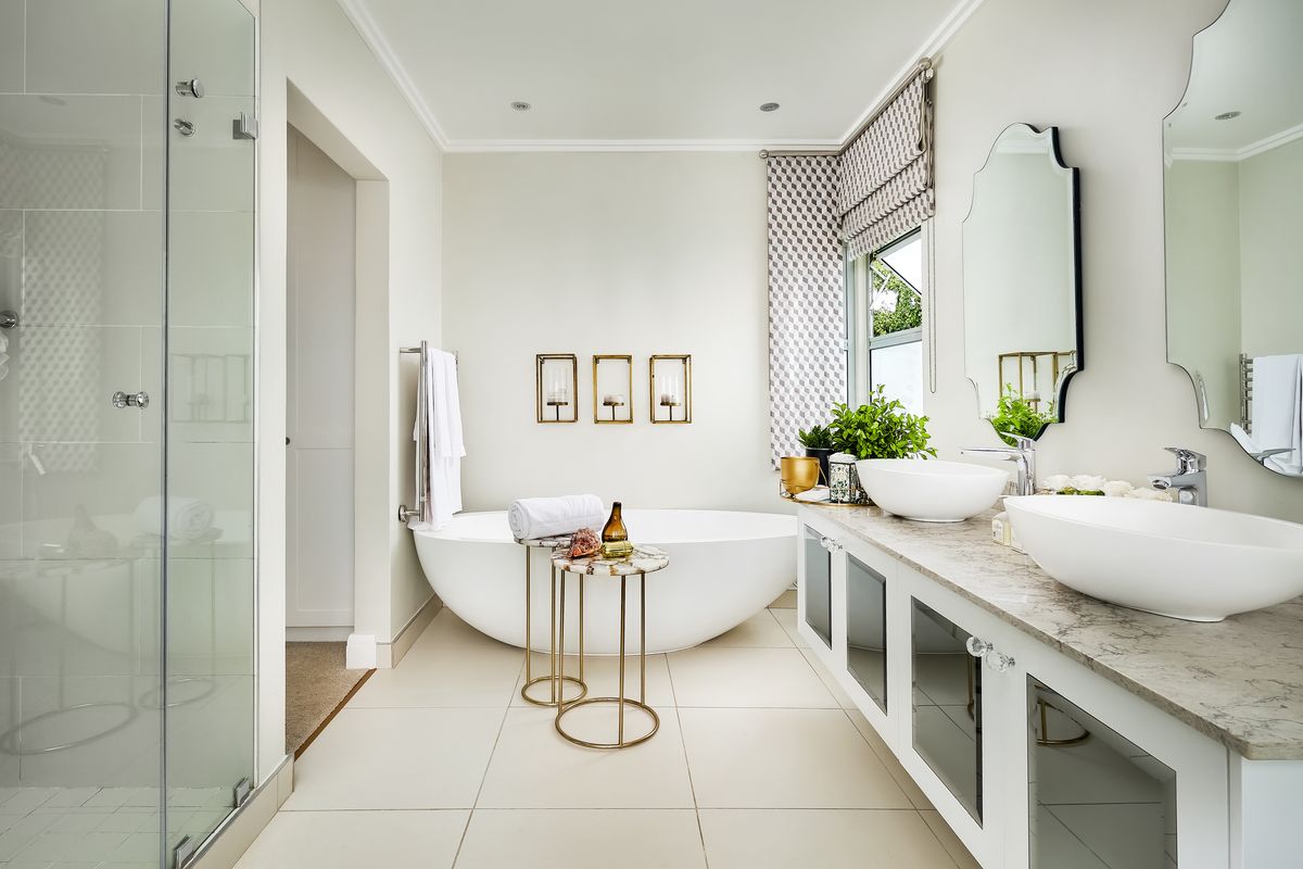 Modern, well-appointed bathroom featuring a freestanding bathtub, double vanity with vessel sinks, and a spacious glass-enclosed shower.