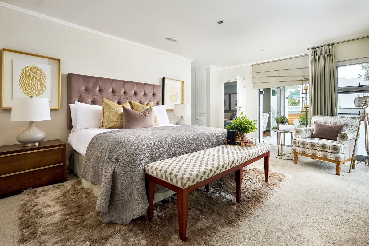A well-appointed bedroom featuring neutral tones, recessed lighting, built-in storage, and direct access to an outdoor patio area through sliding glass doors.