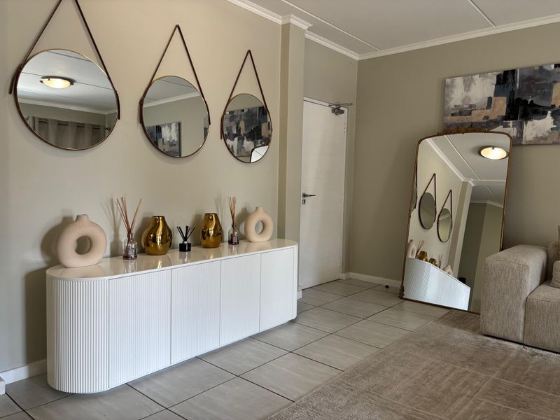 A well-maintained living area featuring neutral wall tones, tiled flooring, and a clean, modern aesthetic with integrated lighting.