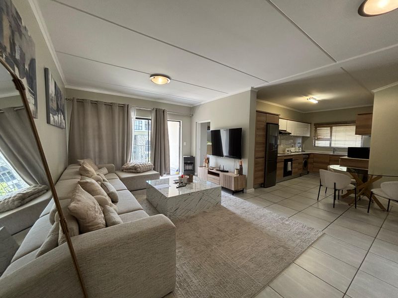 Open-plan living and kitchen area featuring tiled flooring, modern cabinetry, and direct access to a balcony through sliding glass doors.