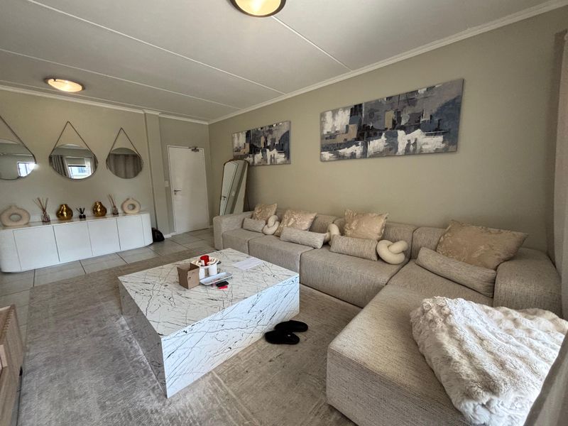 A well-maintained living room featuring neutral wall tones, tiled flooring, and modern flush mount ceiling lighting, creating a comfortable and inviting atmosphere.