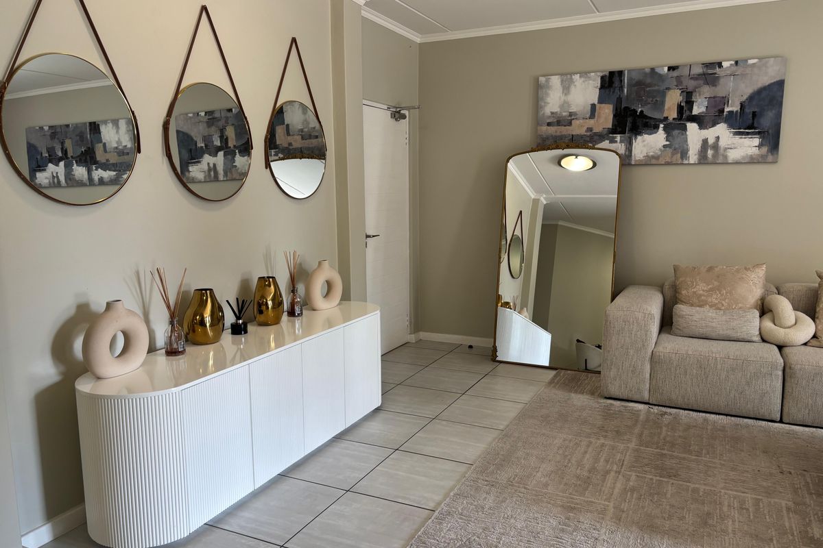 A well-maintained living area featuring neutral wall tones, tiled flooring, and classic ceiling cornicing, creating a bright and inviting atmosphere.