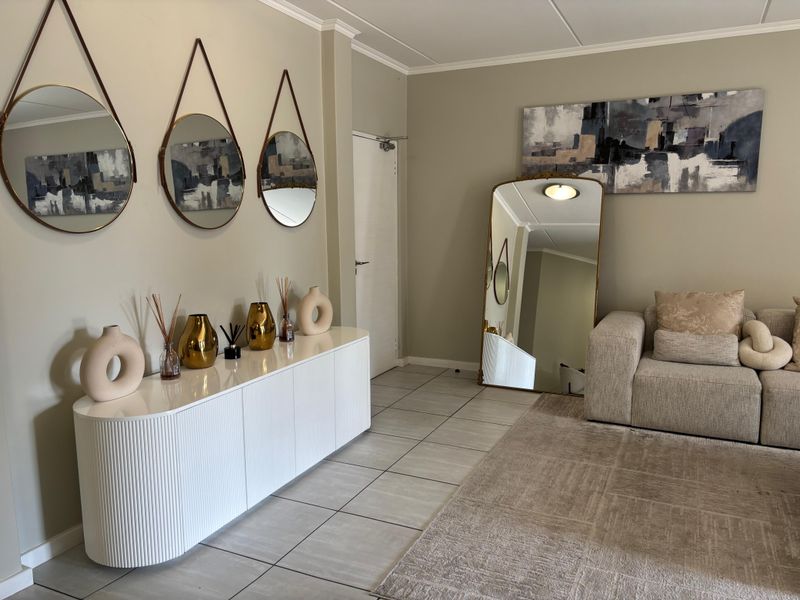 A well-maintained living area featuring neutral wall tones, tiled flooring, and classic ceiling cornicing, creating a bright and inviting atmosphere.