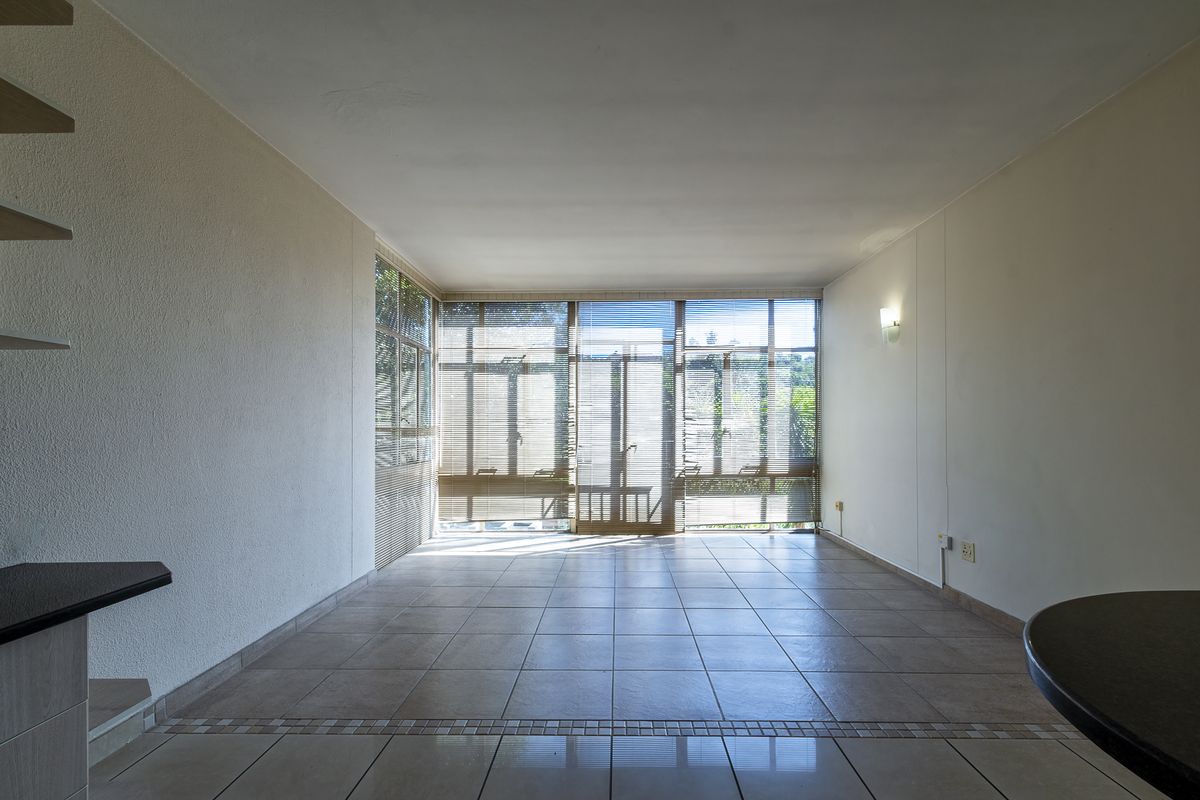 A bright and spacious living area featuring large floor-to-ceiling windows with integrated blinds and neutral tiled flooring throughout.