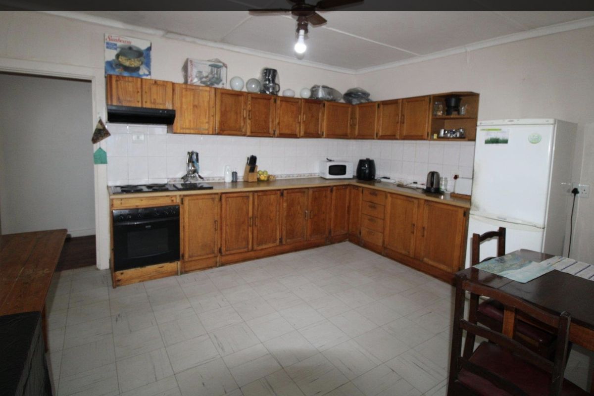 A functional kitchen featuring traditional wooden cabinetry, tiled backsplash, and built-in cooking appliances, offering potential for a modern renovation.