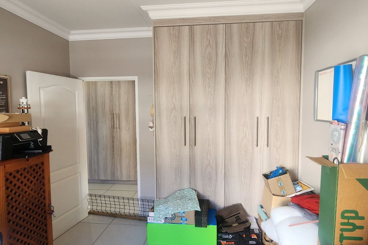 A bedroom featuring built-in wood-grain cabinetry and tiled flooring, offering ample storage space and a neutral interior finish.