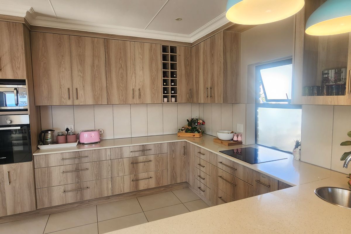 Modern kitchen featuring wood-grain cabinetry, stone countertops, integrated oven, built-in microwave, induction hob, and a stainless steel sink with a contemporary mixer tap.
