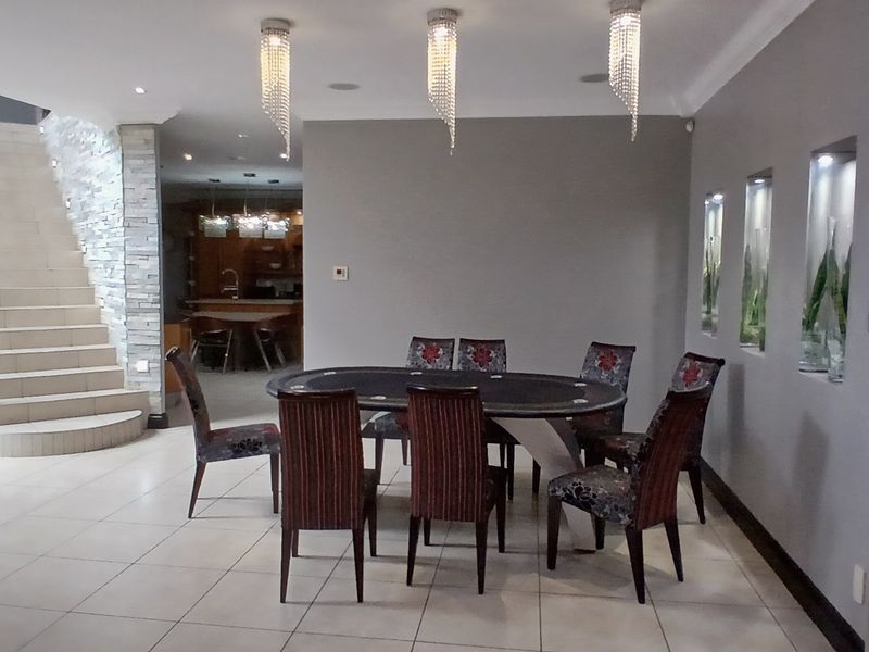 Spacious open-plan dining area featuring tiled floors, a feature stone wall, a staircase with a metal balustrade, and decorative recessed wall niches.