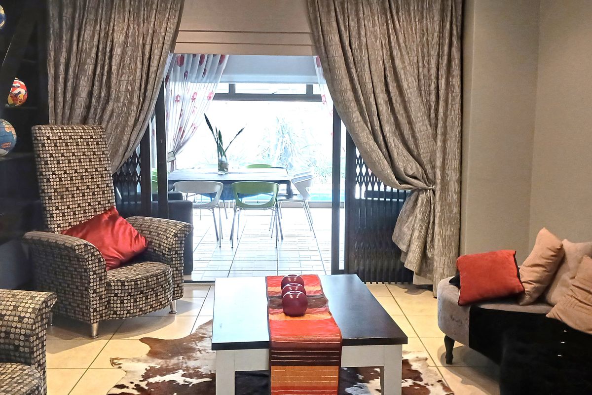 A comfortable living room featuring tiled flooring and large sliding glass doors that provide access to an outdoor patio area.