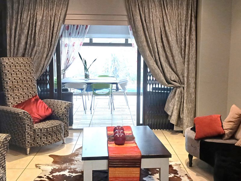 A comfortable living room featuring tiled flooring and large sliding glass doors that provide access to an outdoor patio area.