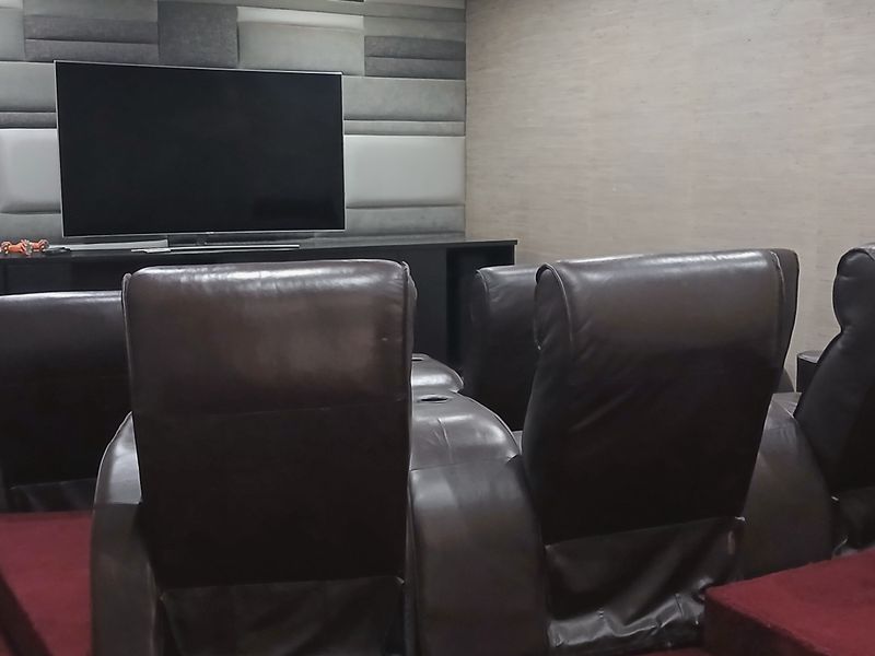 A dedicated home cinema room featuring tiered flooring, acoustic wall paneling, and a built-in media console for an immersive viewing experience.