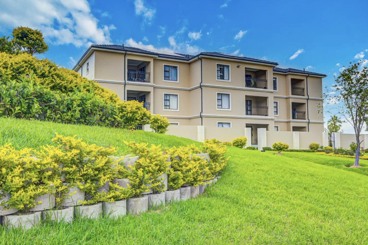 A well-maintained townhouse complex featuring landscaped gardens, retaining walls, and private balconies on multiple levels.