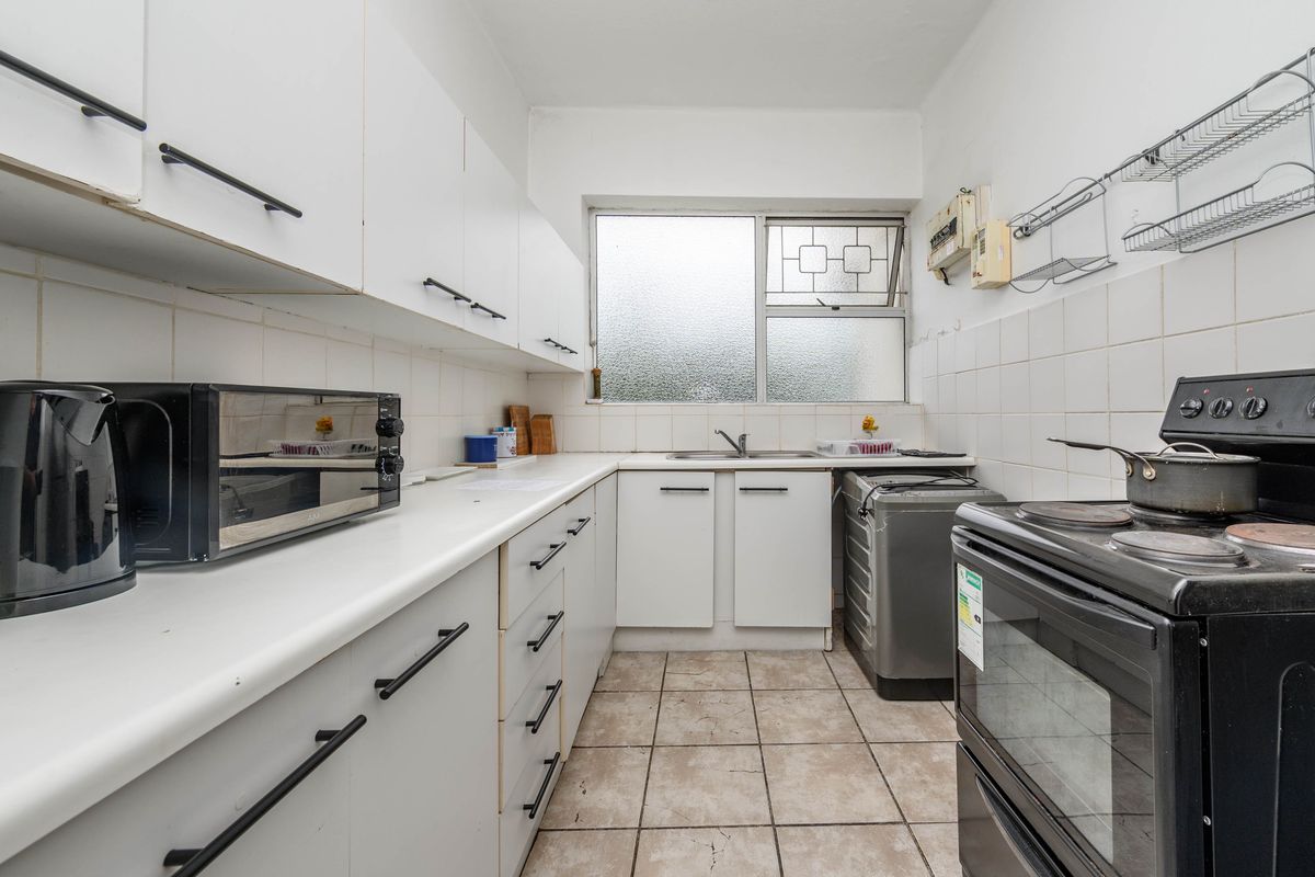 A functional kitchen featuring white cabinetry, laminate countertops, tiled backsplash, and a dedicated space for a washing machine.