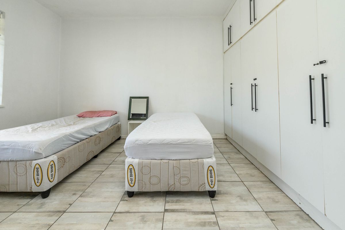A bedroom featuring tiled flooring and extensive floor-to-ceiling built-in cupboards providing ample storage space.