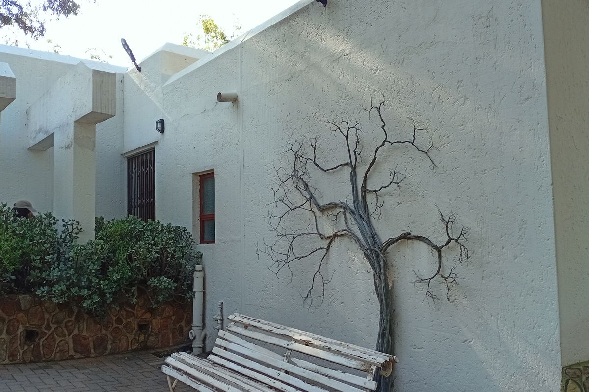 A view of the exterior rear facade featuring textured walls, stone masonry base, and a paved patio area.
