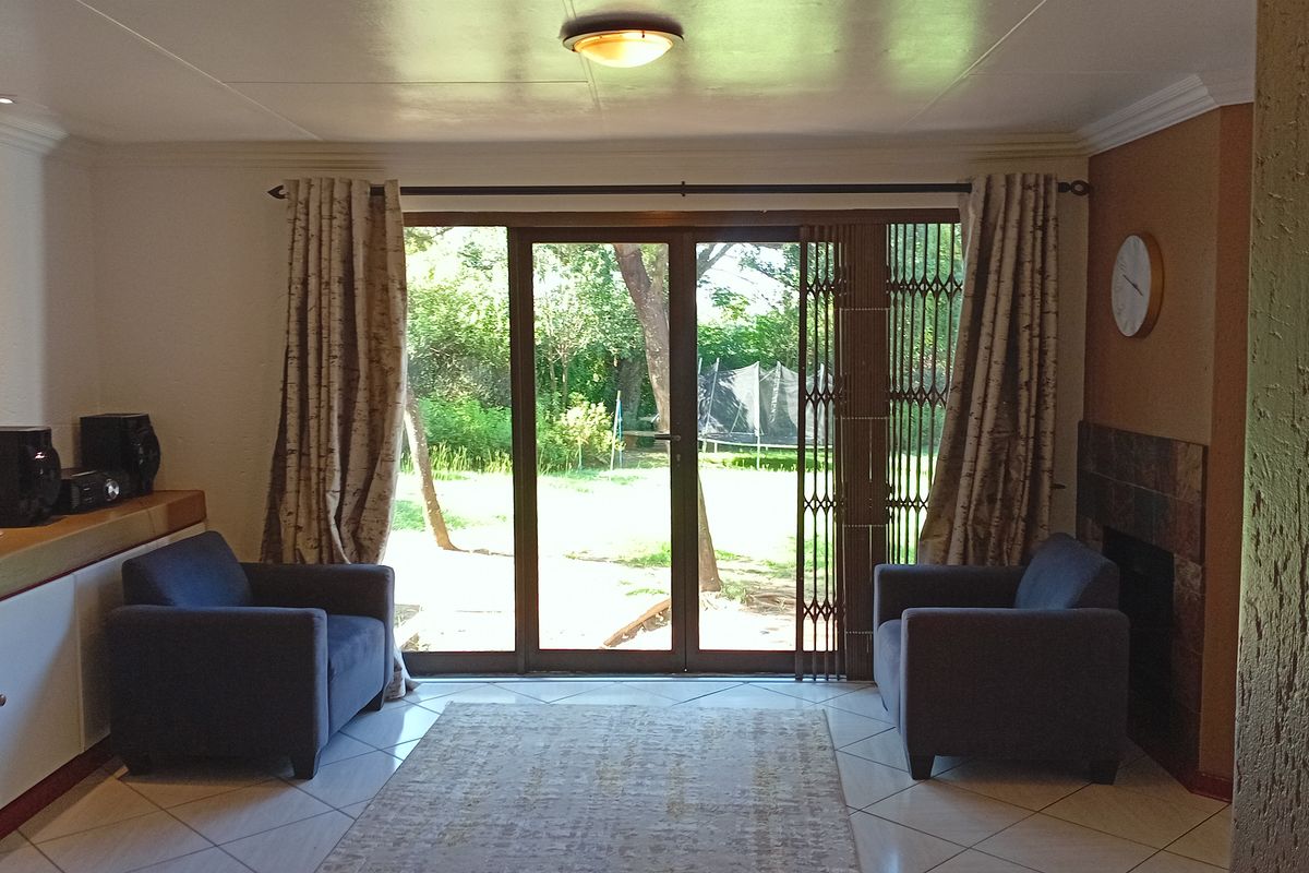 A living room featuring tiled flooring, a built-in fireplace, and sliding glass doors providing direct access to the rear garden.