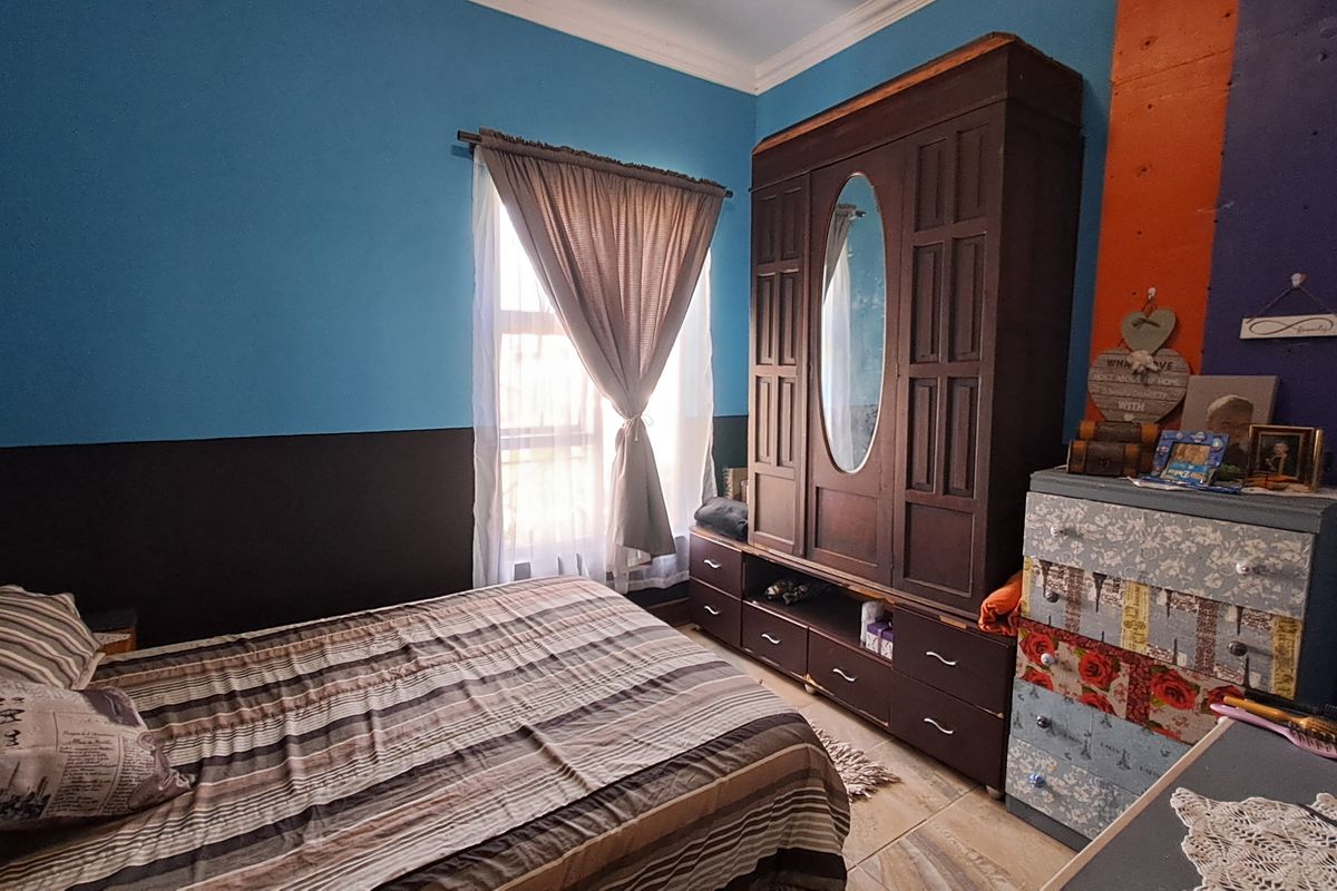 A bedroom featuring tiled flooring and decorative cornicing, currently finished with bold wall paint colors.