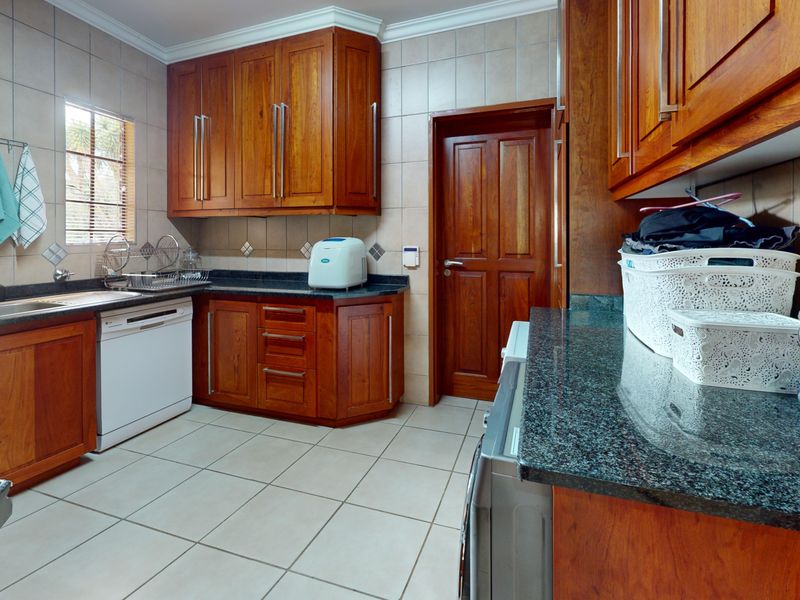 A functional kitchen featuring warm wooden cabinetry, granite countertops, tiled backsplash, and tiled flooring, providing ample storage and workspace.