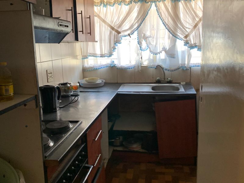 A dated kitchen featuring built-in cabinetry, an electric hob, and an oven, requiring significant renovation and modernization of finishes.