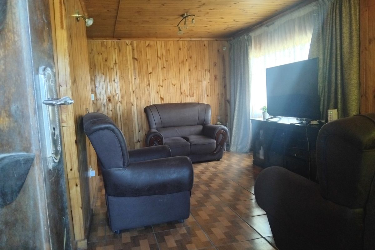 A living room featuring extensive timber wall and ceiling paneling with tiled flooring, offering a rustic aesthetic.